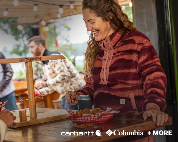 Person wearing a red striped fleece jacket at an outdoor table, with Columbia + MORE logo.