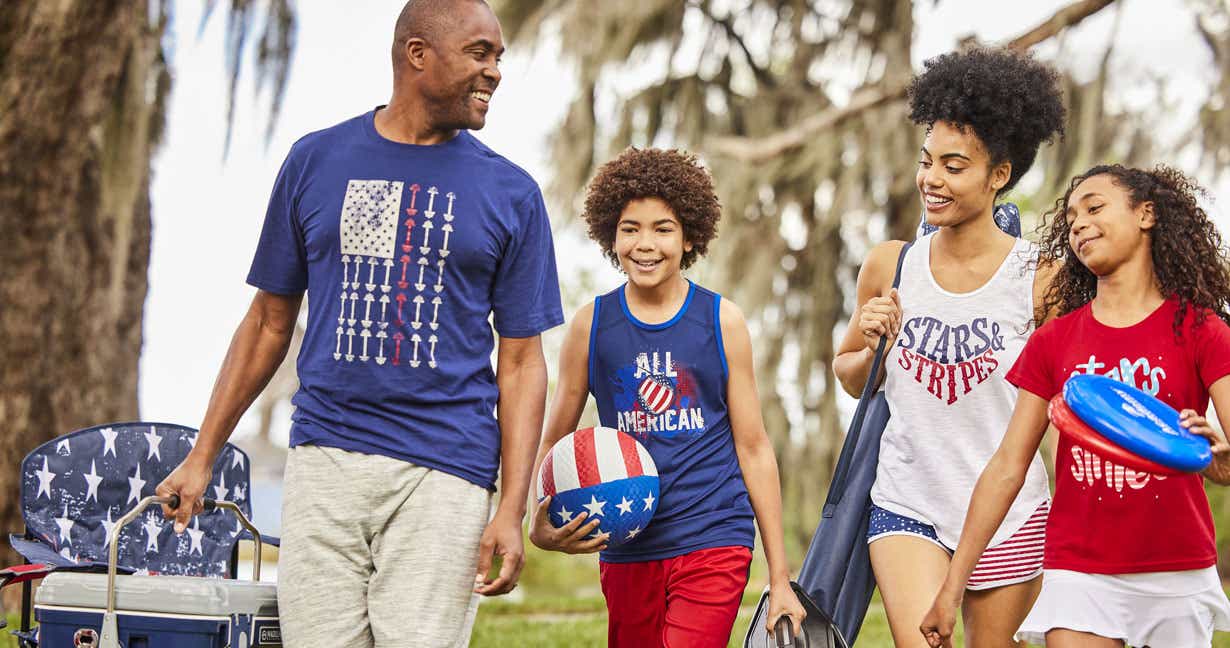 Father walking through a park with his family carrying sports gear