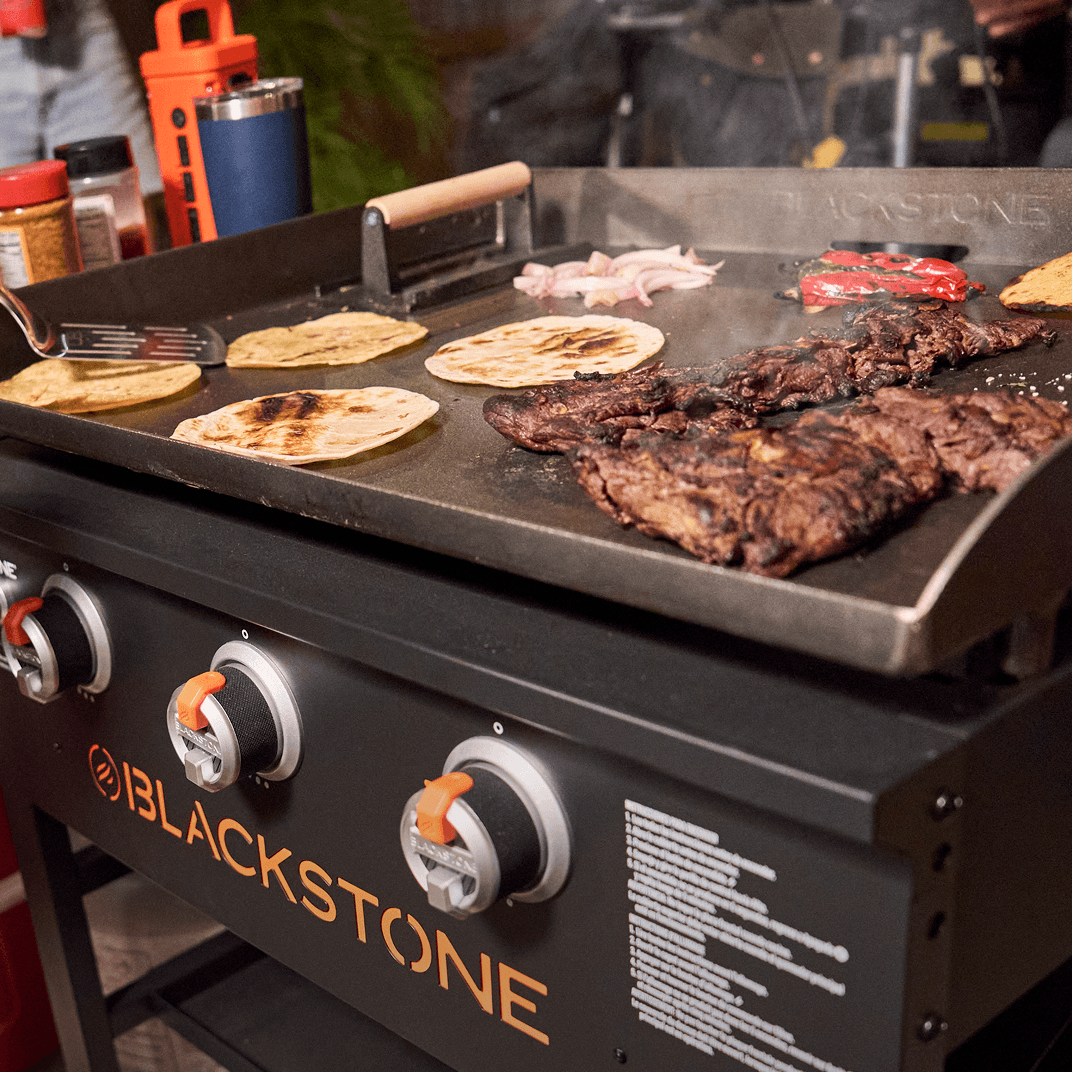 Flat-top griddle cooking burgers and tortillas on an outdoor griddle surface.