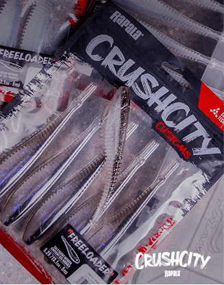 Assorted Crush City fishing lures arranged on a wooden surface, including hard baits and skirted jigs.