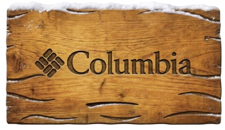 Columbia ogo carved into a weathered wooden surface topped with snow.