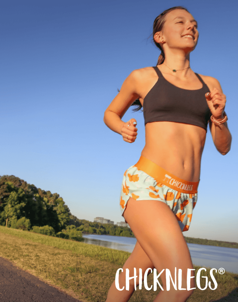Runner wearing athletic shorts and a sports top while jogging on a paved path.