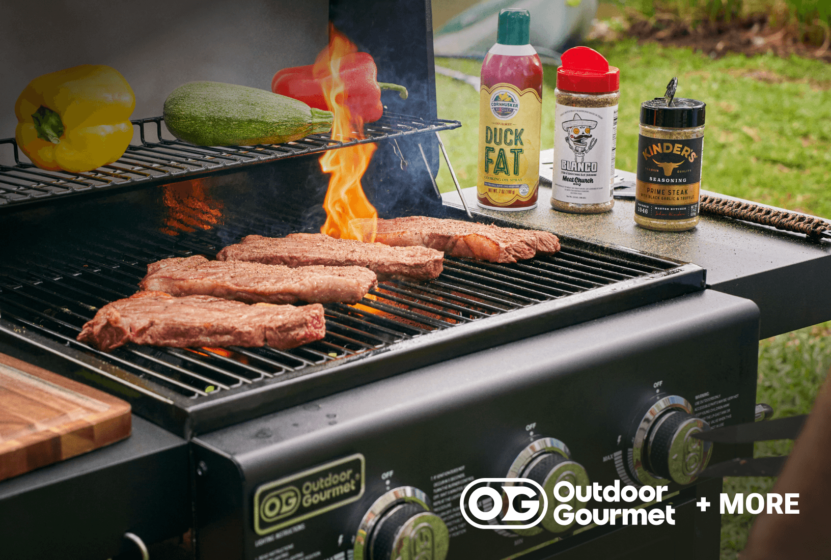Outdoor Gourmet gas grill with steaks cooking over open flames.