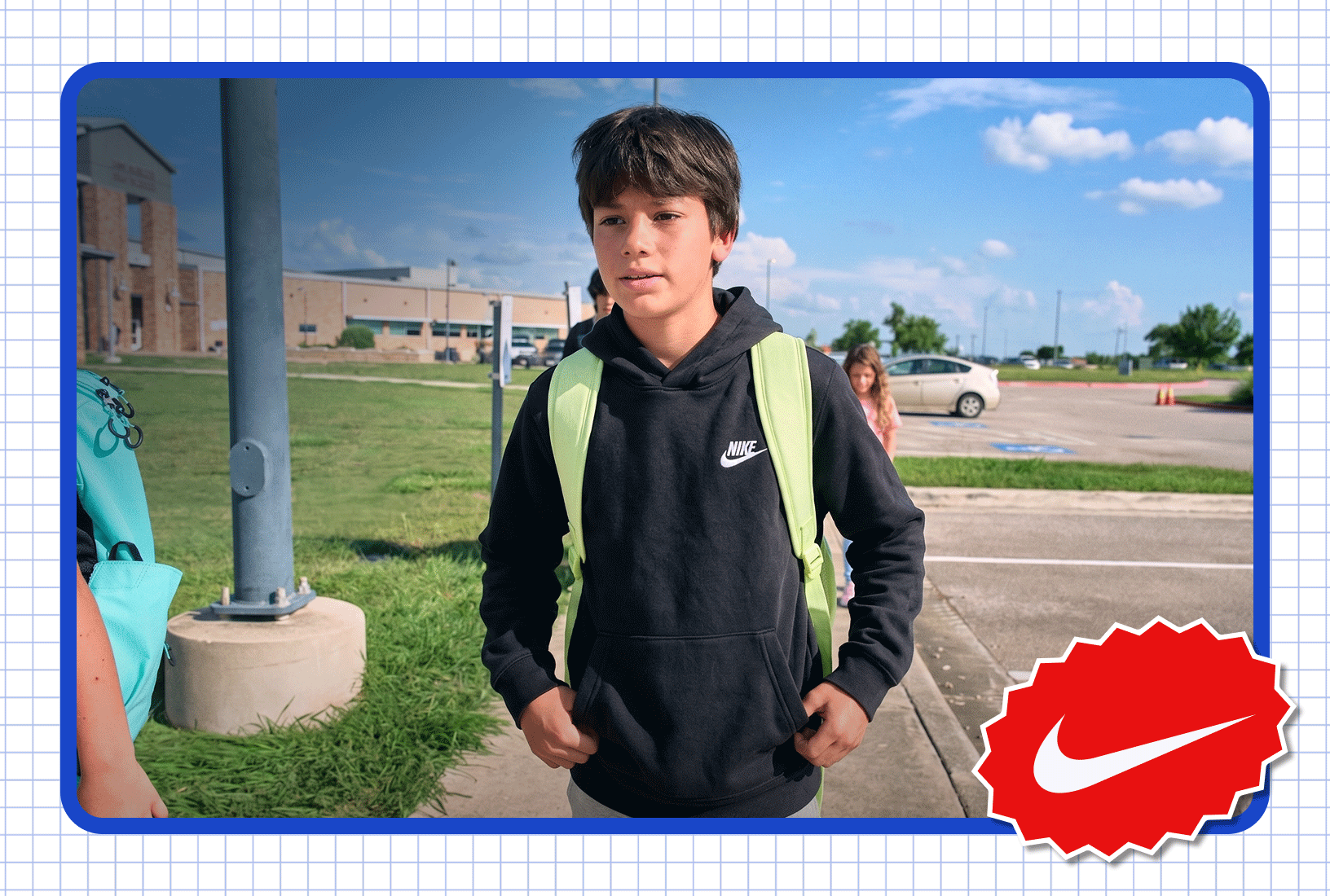 Person wearing a black Nike hoodie and backpack standing outdoors near a school campus.