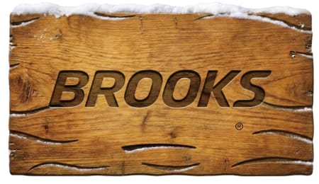 Brooks logo carved into a weathered wooden surface topped with snow.