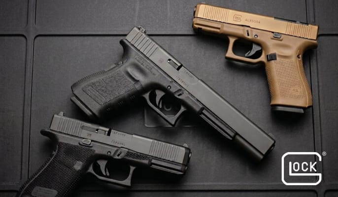 Three Glock semi-automatic pistols displayed on a black textured surface, including two black models and one tan model arranged diagonally.