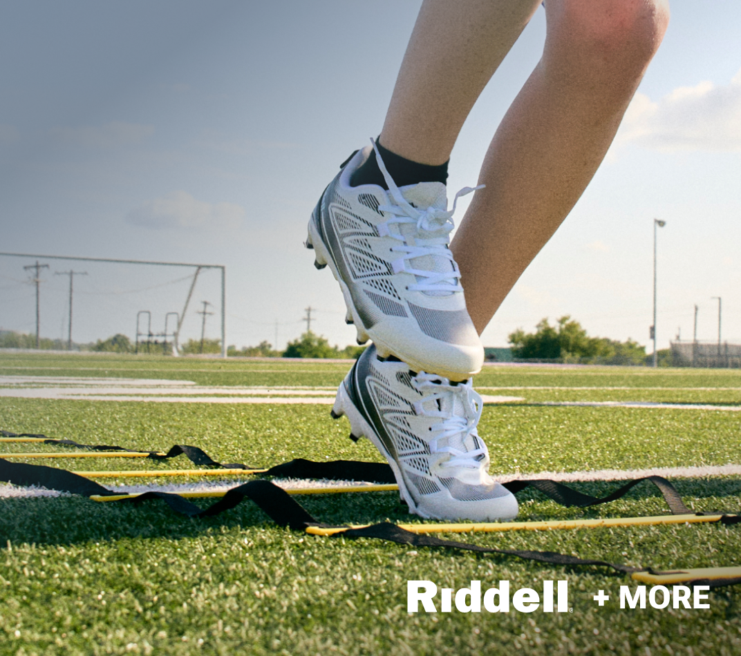 Youth Riddell football cleats stepping through agility ladder on turf field.