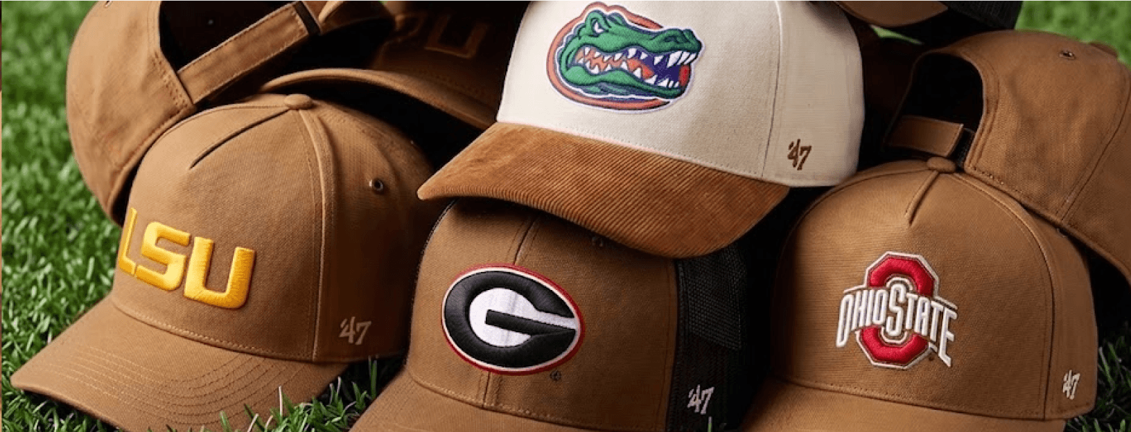 Stack of college baseball caps including LSU, Florida, Georgia, and Ohio State on grass.