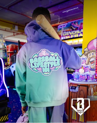 Person wearing a colorful hoodie standing in an arcade surrounded by illuminated game machines.