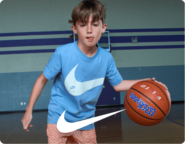 Person in a light blue athletic shirt and white shorts holding a basketball on an indoor court. Nike