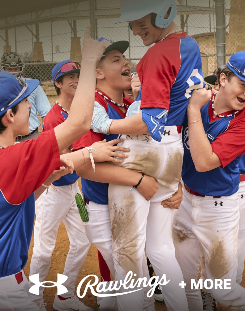 Youth baseball players in red and blue uniforms celebrating together on the field with Under Armour and Rawlings branding.