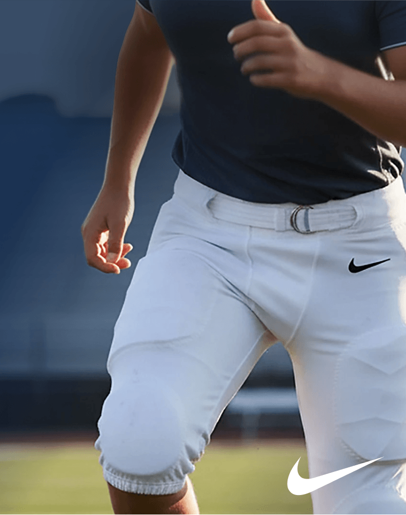 Athlete wearing white integrated football pants while standing on a football field.