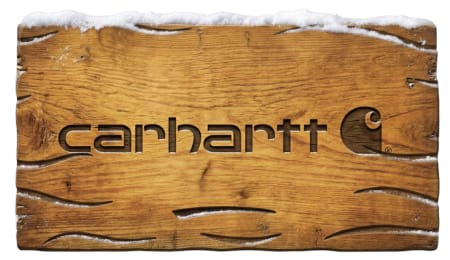 Carhartt logo carved into a weathered wooden surface topped with snow.