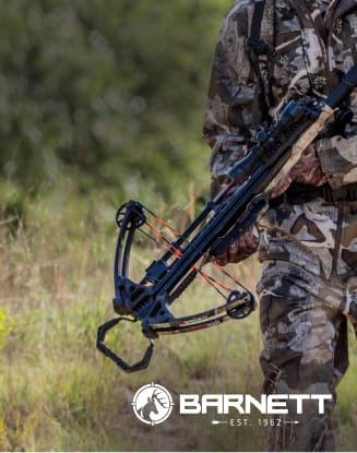Hunter in camouflage holding a scoped crossbow outdoors in a grassy field.