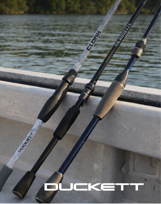 Two Duckett fishing rods resting against the edge of a boat above the water.