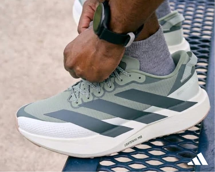 Gray and green running adidas EVO running shoe being adjusted on a bench.