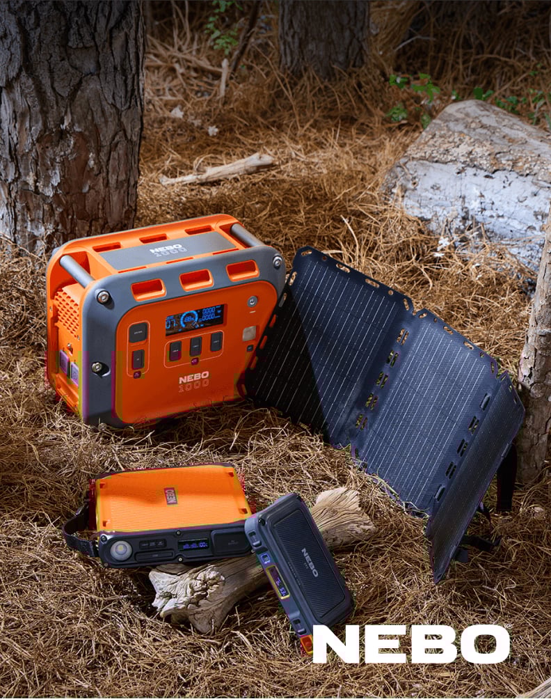 NEBO portable power stations displayed outdoors on the ground alongside a solar panel and flashlight.