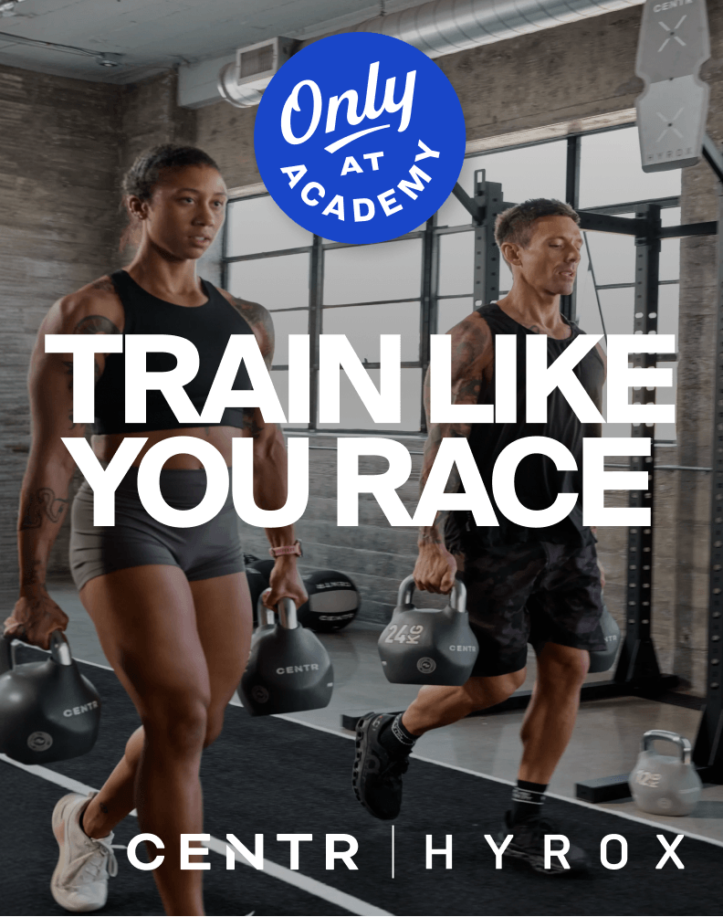 Two athletes carrying kettlebells in a gym with Centr x Hyrox equipment.