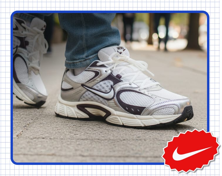 Nike athletic sneaker worn on a sidewalk, shown in close-up with Nike brand logo badge in the lower corner.