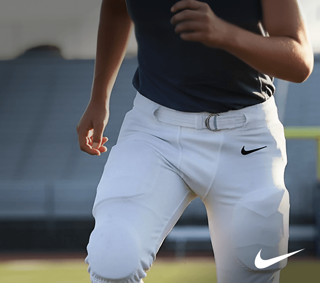 Youth football player wearing white Nike integrated football pants in action.