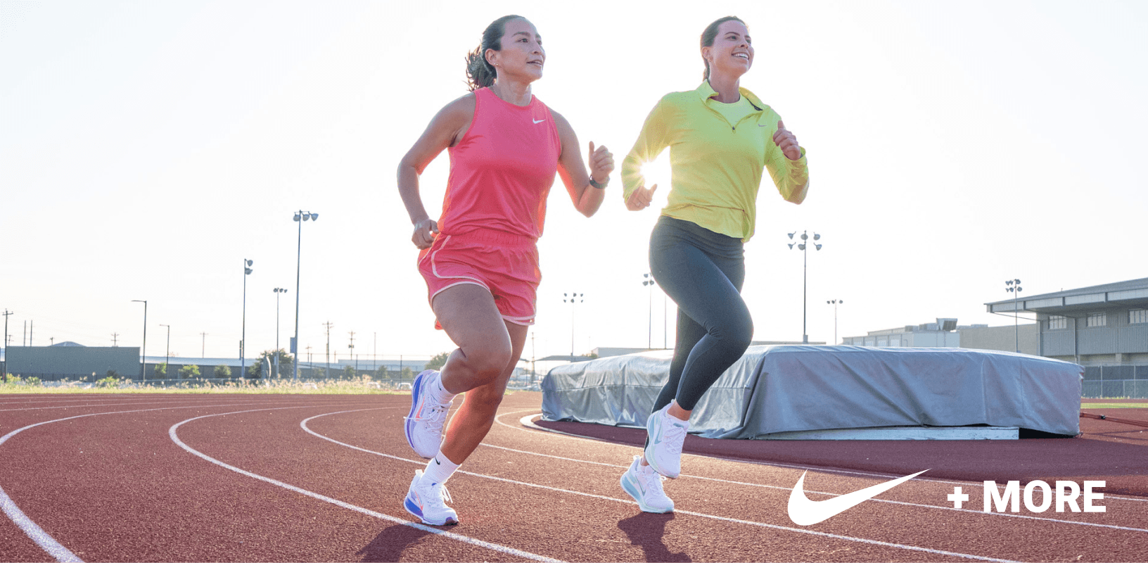 Two women running on outdoor track wearing colorful athletic clothing.