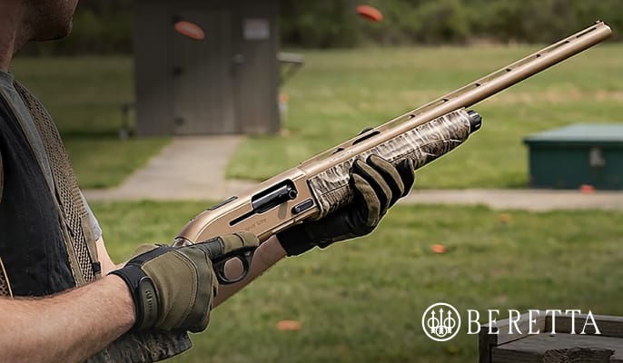 Close-up of a person holding a camouflage Beretta A300 Ultima shotgun outdoors at a shooting range, featuring an Only at Academy badge and Beretta logo.