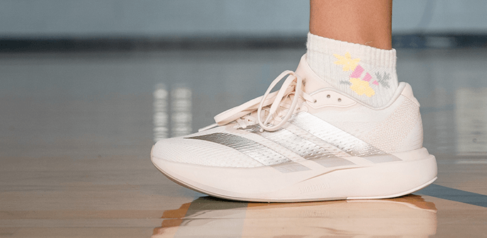 Close up of pink adidas sneaker on gym floor.
