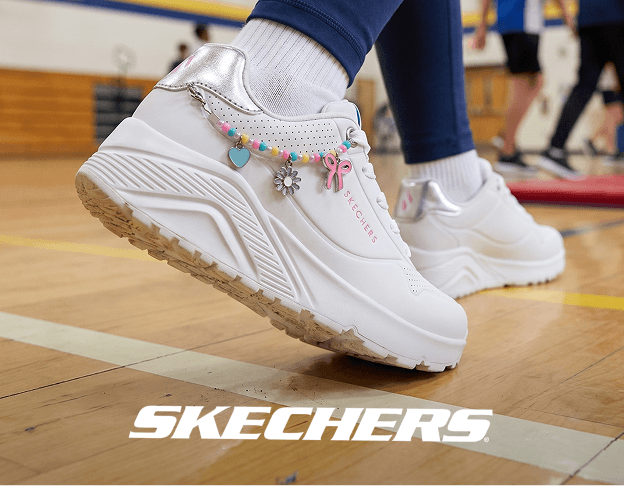 Close-up of white SKECHERS sneakers with colorful accents on a gym floor. SKECHERS