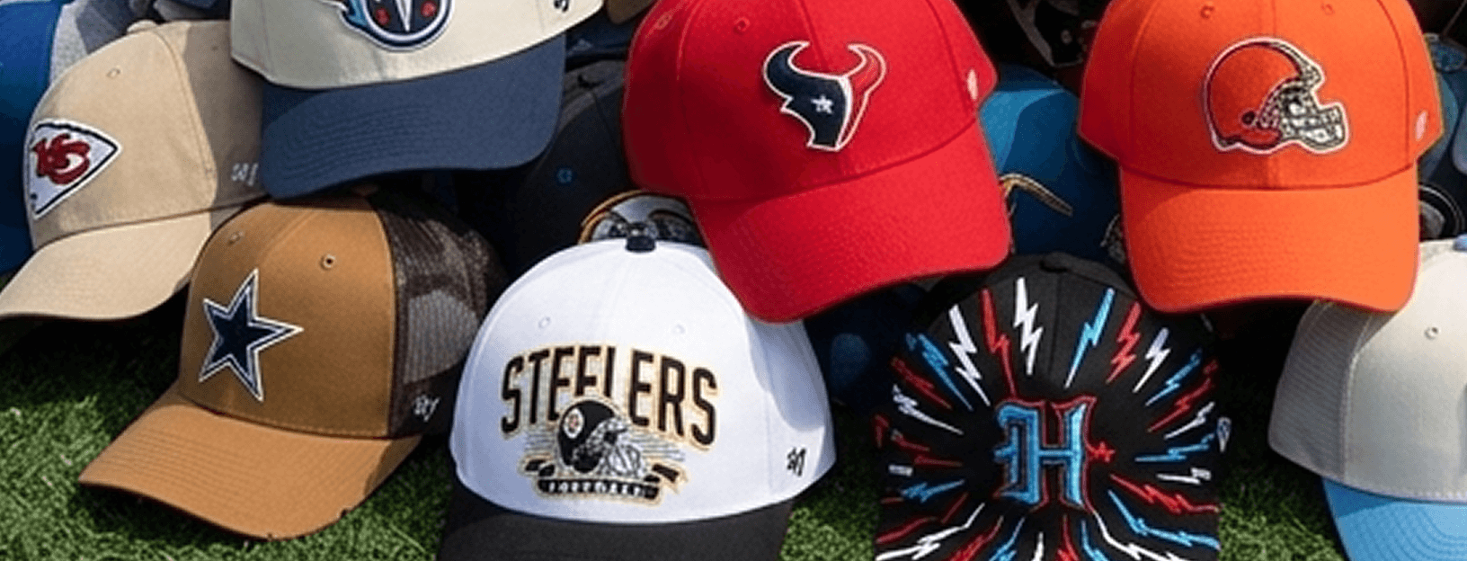 Assortment of NFL team hats and beanies displayed on turf, including caps featuring team logos from Dallas, Pittsburgh, Houston, Cleveland, Tennessee, and Kansas City.