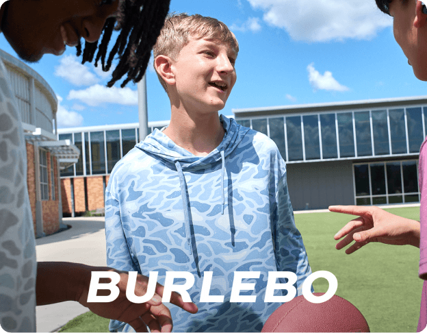 Person outdoors wearing a blue BURLEBO shirt near a brick building. BURLEBO