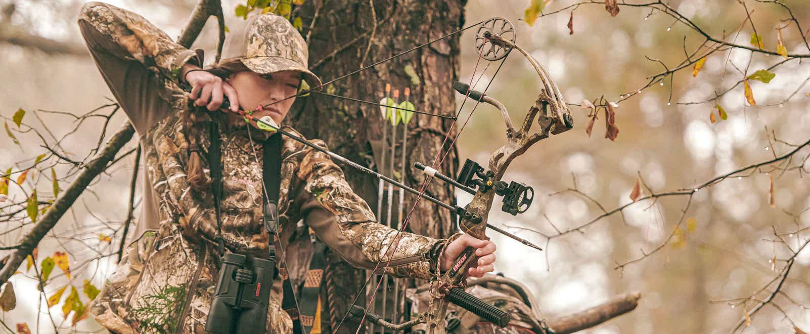 Bowhunter readies her shot from a tree stand