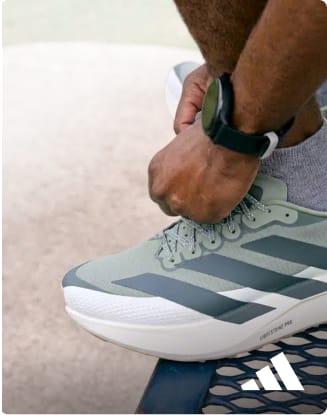 Person adjusting a gray and green adidas EVO running shoe.