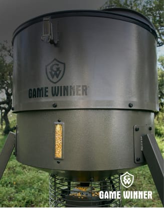 Game Winner deer feeder standing outdoors in a grassy area.