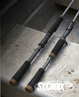 Close-up of two St. Croix fishing rod handles with black grips resting on a metal surface. St. Croix logo shown.