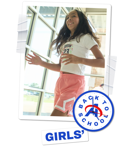 Girls’ back-to-school category banner featuring girls playing indoors and jumping in a school gym.