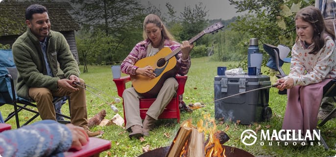 Person sitting in a camp chair near a campfire roasting a marshmallow at an outdoor campsite.