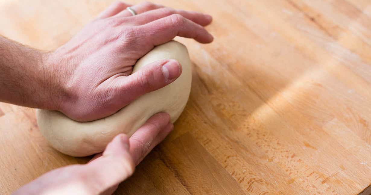 Dough ball being rolled out by hands
