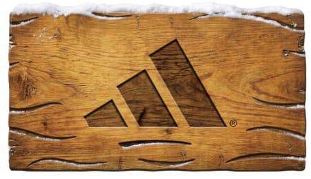 adidas logo carved into a weathered wooden surface topped with snow.