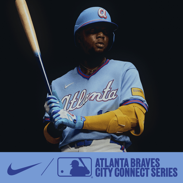 Professional baseball player wearing a light blue Atlanta Braves City Connect jersey and cap, holding a bat in dramatic studio lighting.