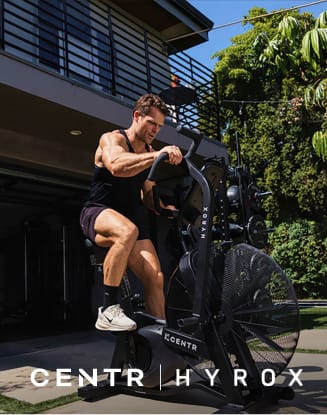 Person exercising on a CENTR HYROX fitness machine outdoors.