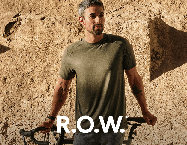 Person wearing a R.O.W. olive green T-shirt standing outdoors in a dry, rocky landscape.