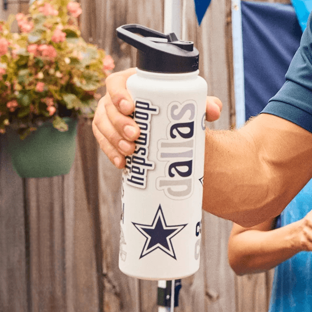 Hand holding a white Dallas Cowboys themed tumbler with team logo and script design.