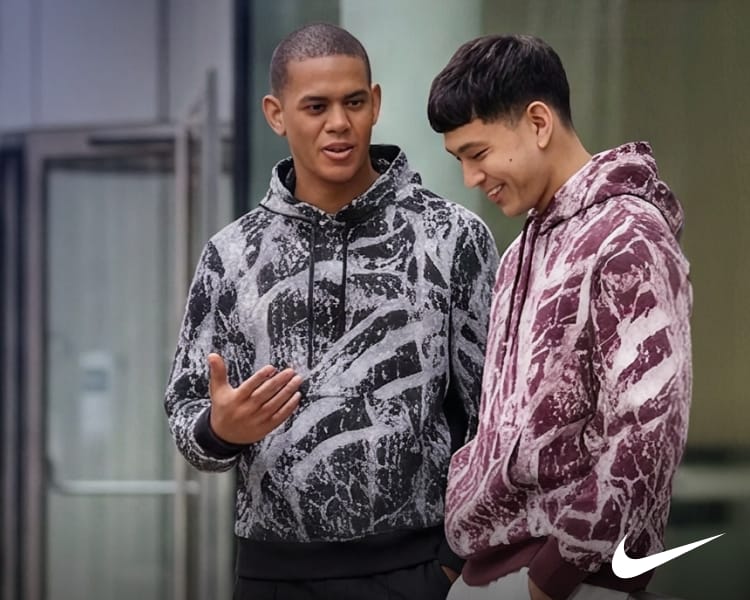 Two people wearing graphic hoodies in black and burgundy colorways.