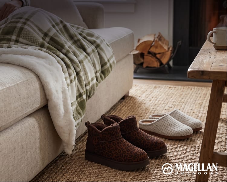 Cozy bedroom scene featuring a bed with plaid bedding and brown slippers on a wood floor beside a bedside table.