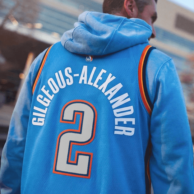 Back view of a light blue NBA basketball jersey worn over a hoodie showing the name GILGEOUS-ALEXANDER and the number .