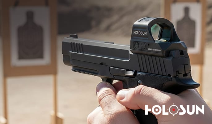 Hand holding a pistol equipped with a Holosun red dot sight at a shooting range. Holosun logo appears in the lower-right corner.