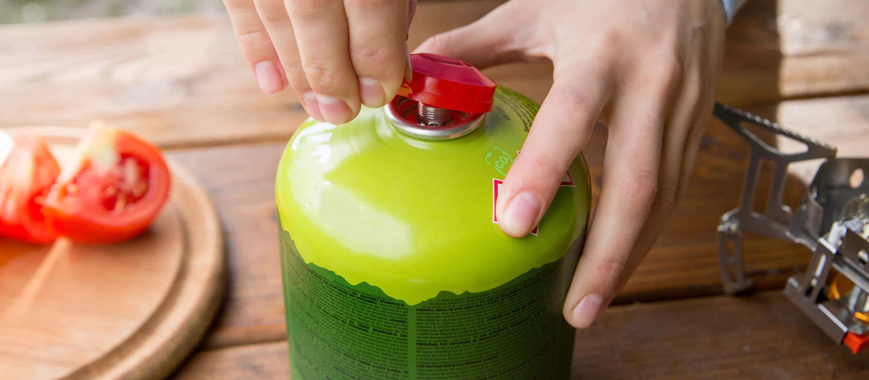 A person takes off the plastic cap of a propane canister
                        