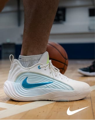 Nike Giannis Immortality 5 basketball shoe in white with blue accents displayed on an indoor basketball court beside a basketball.