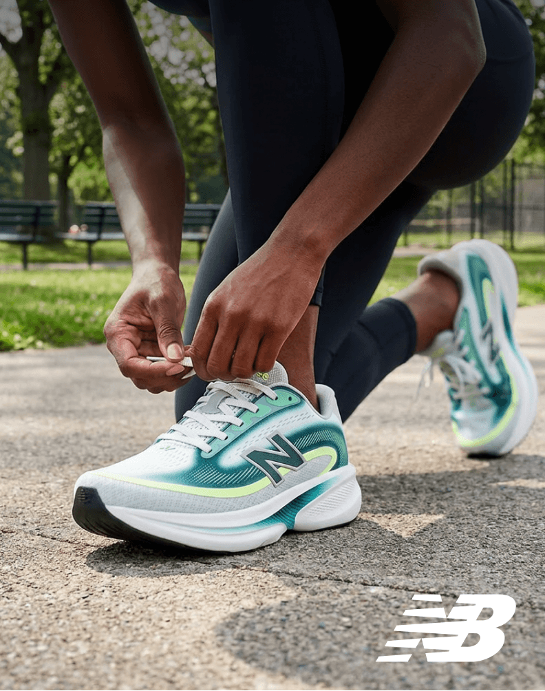 Runner tying laces on New Balance Ellipse running shoes on an outdoor path.