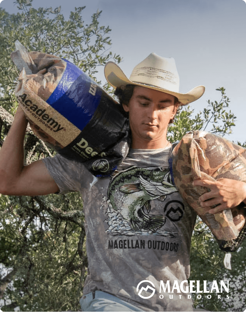 Person holding bag of decoys outdoors wearing a hat and a Magellan Outdoors washed camo tee.